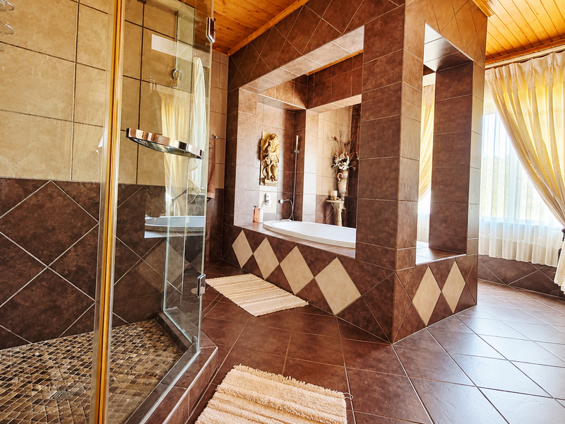Spacious bathroom featuring a built-in bathtub set within a tiled alcove, a separate glass-enclosed shower, and warm timber ceiling finishes.