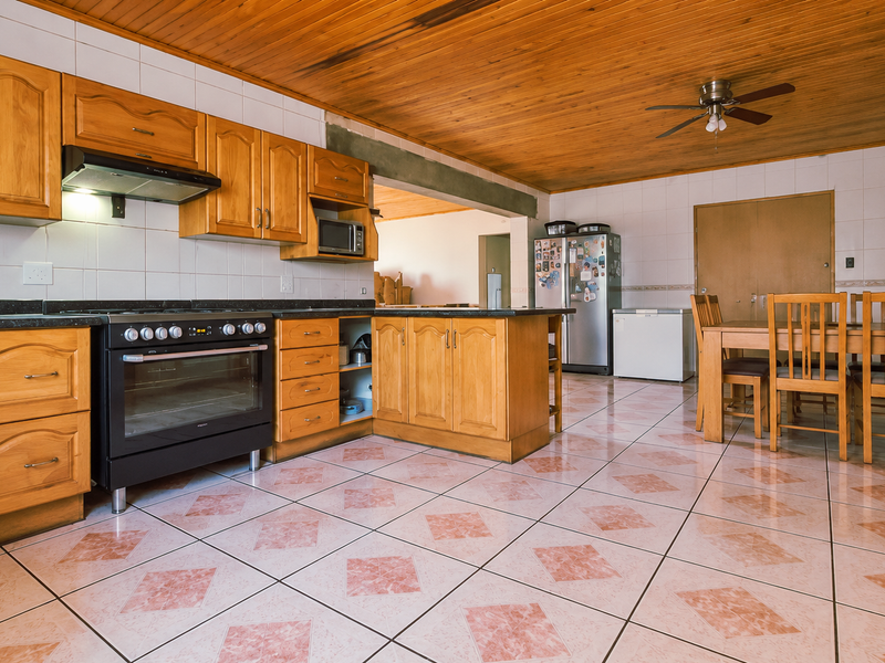 Spacious open-plan kitchen and dining area featuring wooden cabinetry, a built-in oven, tiled flooring, and a distinctive wooden ceiling.