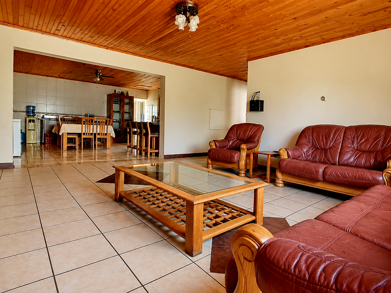 Spacious open-plan living and dining area featuring warm timber ceilings and neutral ceramic floor tiles, seamlessly connecting to the kitchen space.