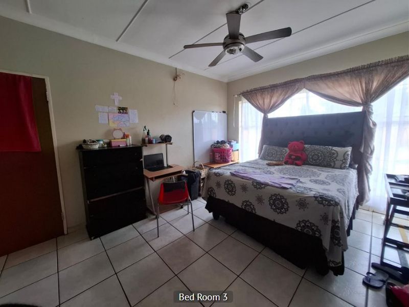 A bedroom featuring tiled flooring and a ceiling fan, with neutral wall finishes and natural light provided by a large window.