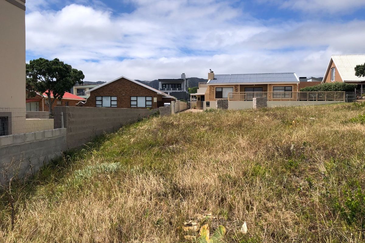 A view of a vacant residential plot featuring established boundary walls and fencing, situated in a developed neighborhood setting.