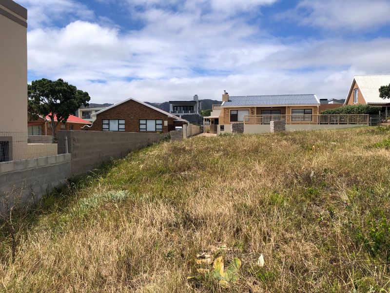 A view of a vacant residential plot featuring established boundary walls and fencing, situated in a developed neighborhood setting.