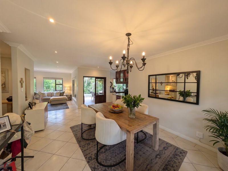 Spacious open-plan dining and living area featuring tiled floors, recessed lighting, and seamless flow to an outdoor patio through a glass sliding door.