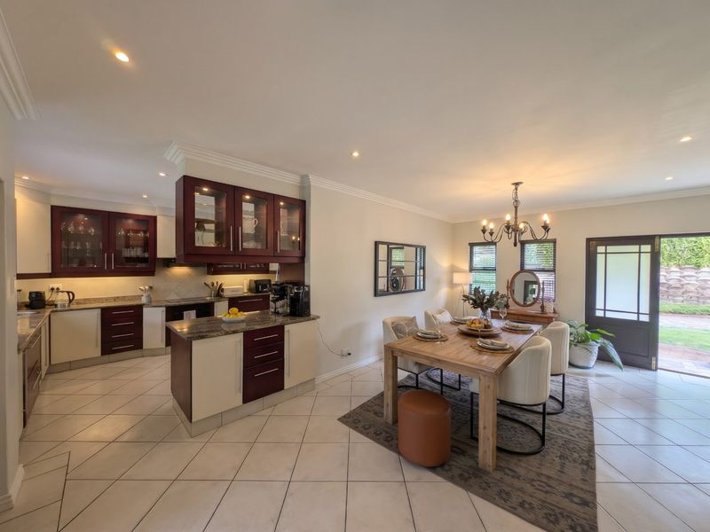 Spacious open-plan kitchen and dining area featuring modern two-tone cabinetry, granite countertops, tiled flooring, and direct access to the outdoor garden space.