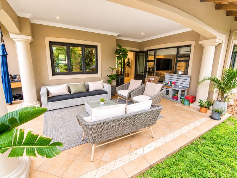 A spacious covered patio featuring tiled flooring, decorative columns, and recessed lighting, providing a seamless transition between the indoor living area and the garden.