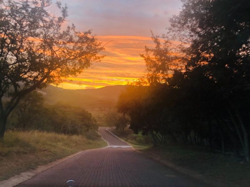 A scenic view of a paved access road leading through a natural landscape at sunset.