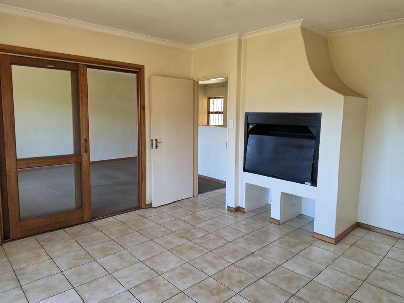 An empty living room featuring tiled flooring, a built-in fireplace, and a wooden sliding door leading to an adjacent space.