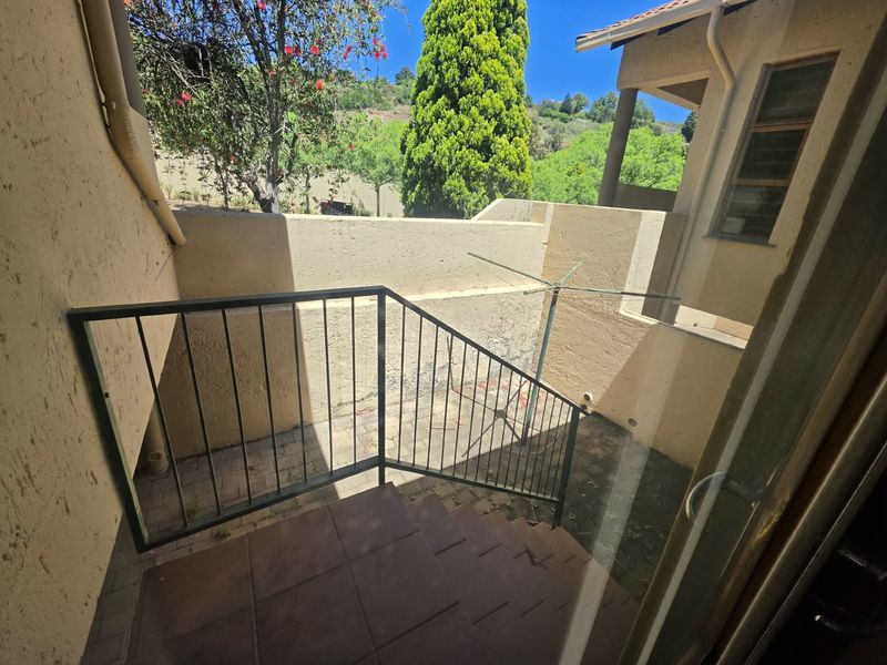 A private outdoor patio area featuring paved flooring, a metal balustrade, and masonry boundary walls, offering a functional space for outdoor use.