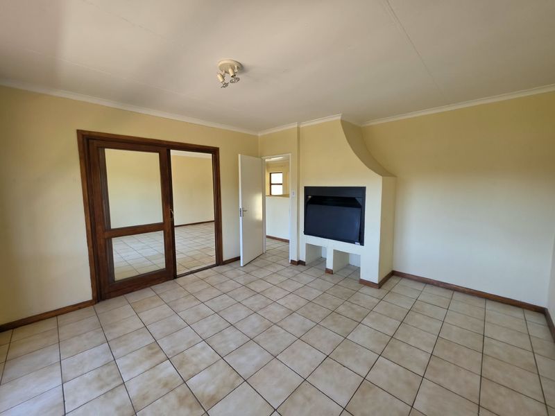 An empty living room featuring ceramic tile flooring, a built-in fireplace, and a wooden sliding door leading to an adjacent space.
