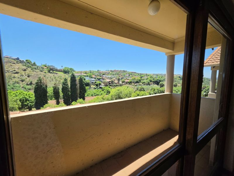 A covered balcony featuring tiled flooring and a support column, offering scenic views of the surrounding landscape and neighborhood.