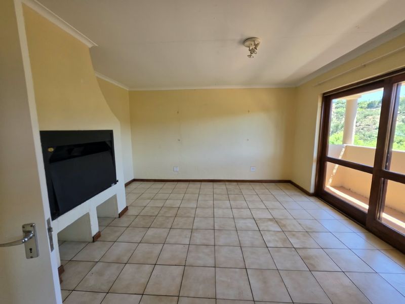 An empty living room featuring ceramic floor tiles, a built-in fireplace, and a sliding glass door leading to an outdoor area.