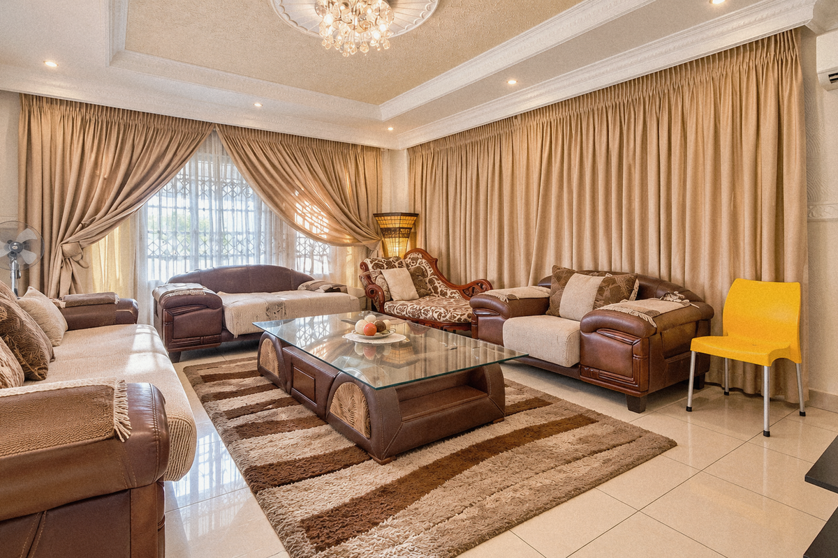 A spacious living room featuring tiled flooring, decorative crown molding, recessed ceiling details, and a wall-mounted air conditioning unit.