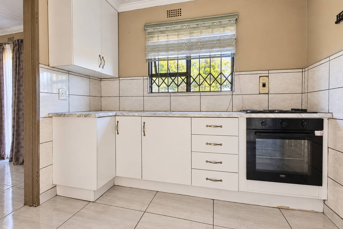 A functional kitchen featuring white cabinetry, tiled backsplash, built-in oven and hob, and ceramic floor tiles.