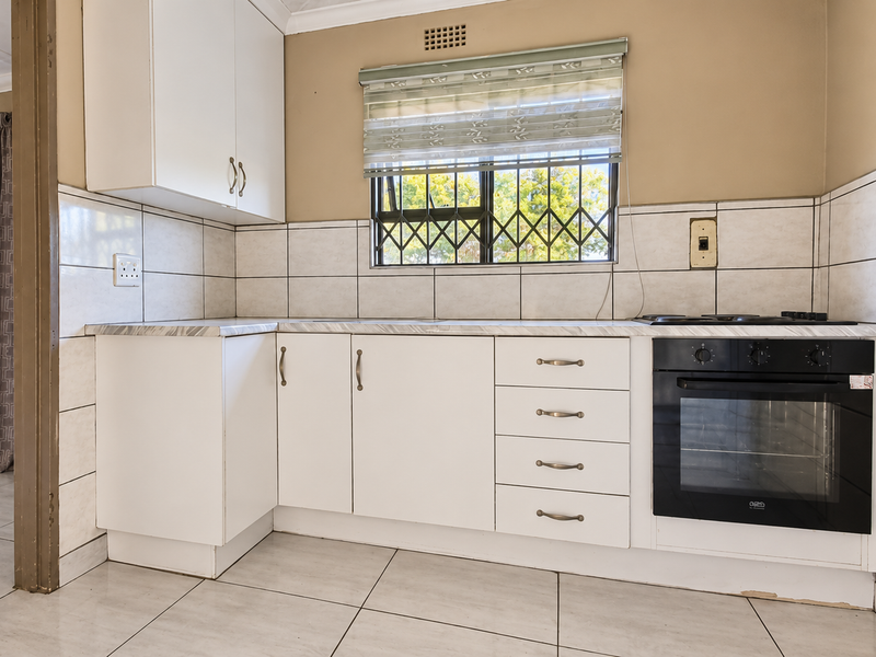 A functional kitchen featuring white cabinetry, tiled backsplash, built-in oven and hob, and ceramic floor tiles.