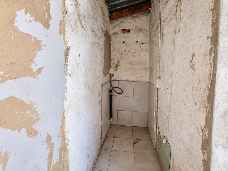 A small utility space featuring tiled flooring and splashback, currently in need of significant renovation and finishing to the wall surfaces and electrical installations.