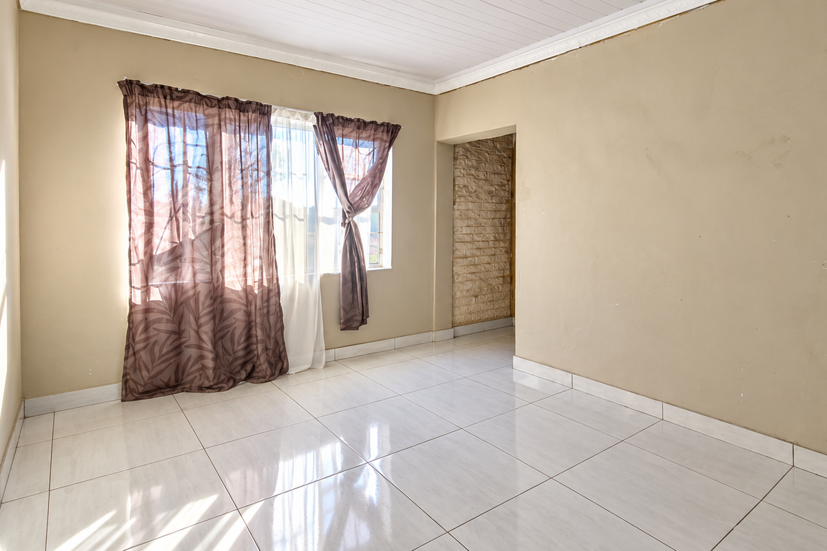A vacant bedroom featuring polished tiled flooring, a timber ceiling, and an exposed brick accent wall, offering a neutral canvas for personalization.