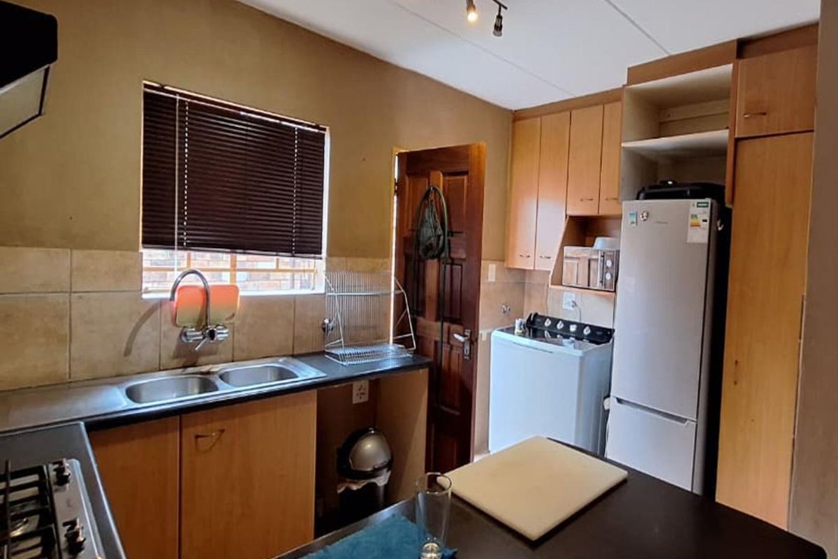 Functional kitchen featuring laminate cabinetry, double sink, built-in hob, and extractor fan, offering a practical layout with potential for modern updates.