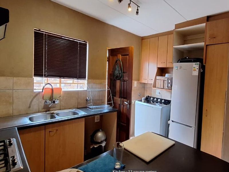 Functional kitchen featuring laminate cabinetry, double sink, built-in hob, and extractor fan, offering a practical layout with potential for modern updates.