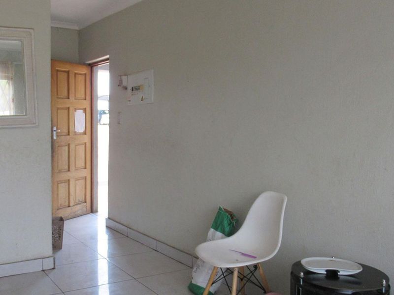 An entry area featuring tiled flooring and a timber panel door, providing access to the apartment interior.