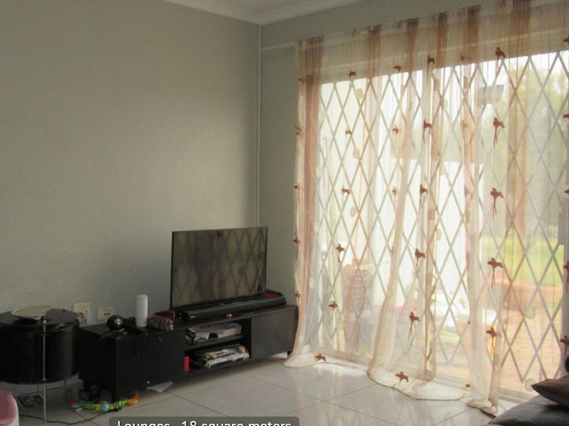 A living room featuring tiled flooring and a sliding glass door with an integrated security gate, providing access to the exterior.