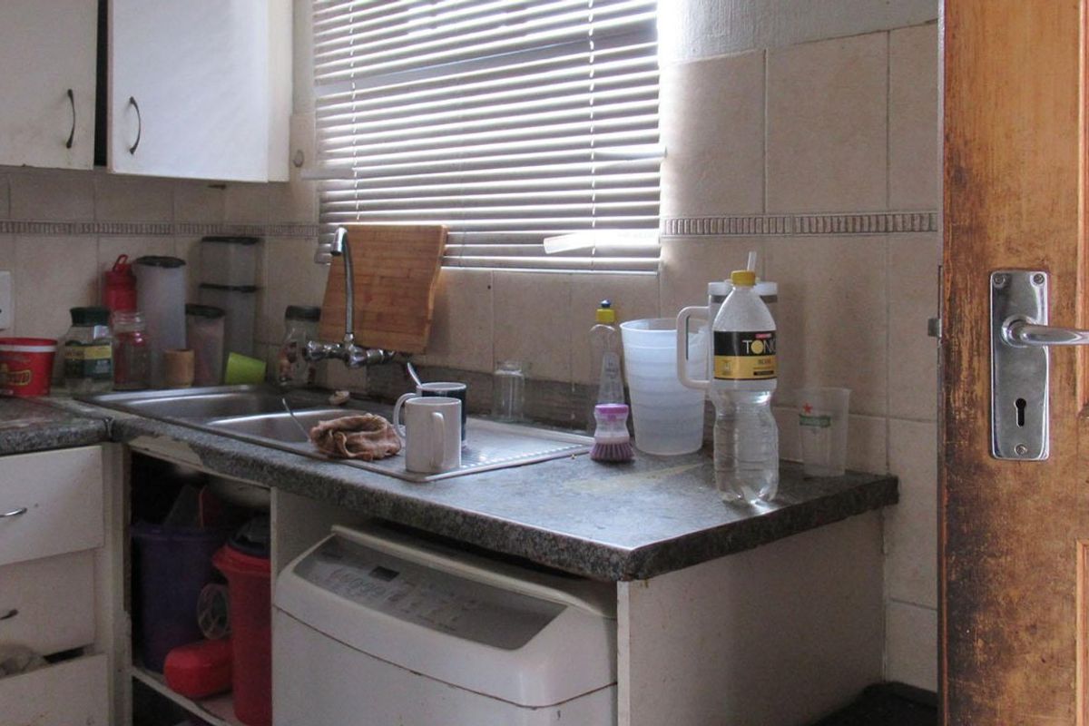 A compact kitchen area featuring a stainless steel sink, tiled backsplash, and built-in cabinetry with laminate countertops.