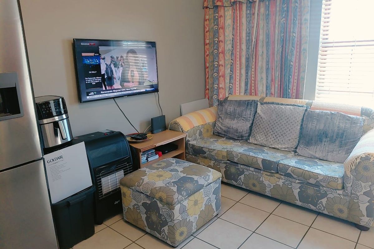 A living room area featuring tiled flooring and window blinds, providing a functional space for relaxation.