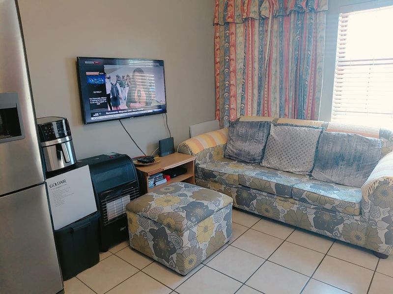 A living room area featuring tiled flooring and window blinds, providing a functional space for relaxation.