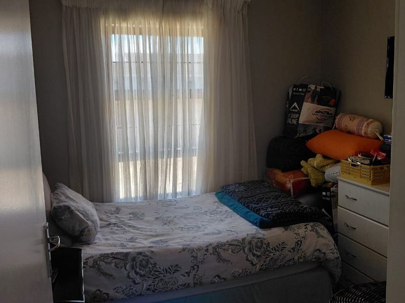 A compact bedroom featuring a window with sheer curtains, providing natural light to the space.