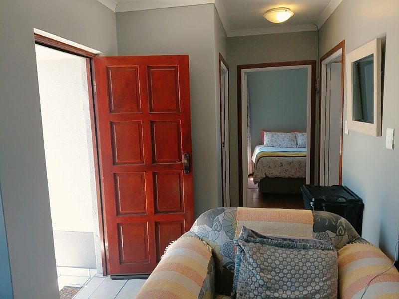A functional hallway connecting the entrance to the bedroom area, featuring neutral wall tones and traditional timber door frames.