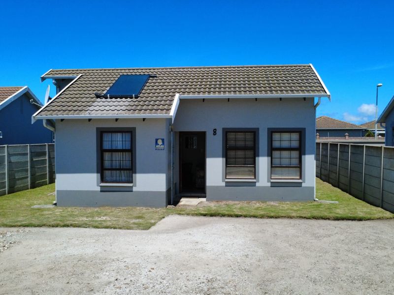 Front elevation of a detached house featuring a tiled roof with a solar water heating panel, precast boundary walls, and a gravel driveway.