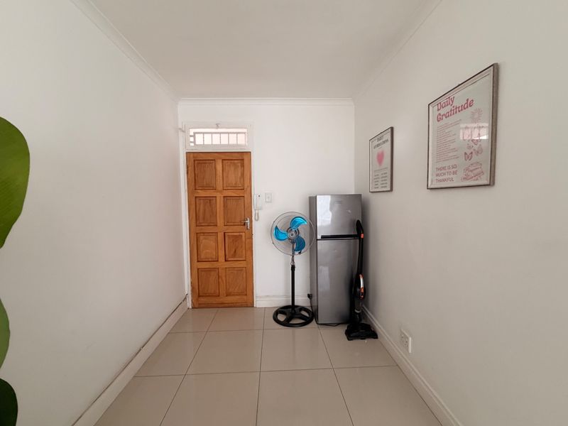 A clean and bright entrance area featuring tiled flooring, a solid timber panel door with a transom window, and an integrated intercom system.
