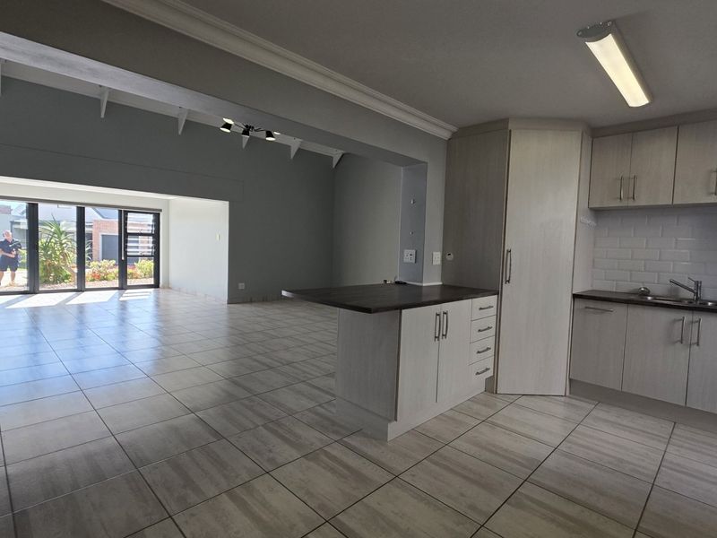 Spacious open-plan living area featuring a modern kitchen with light wood cabinetry, subway tile backsplash, and large sliding doors leading to the exterior.