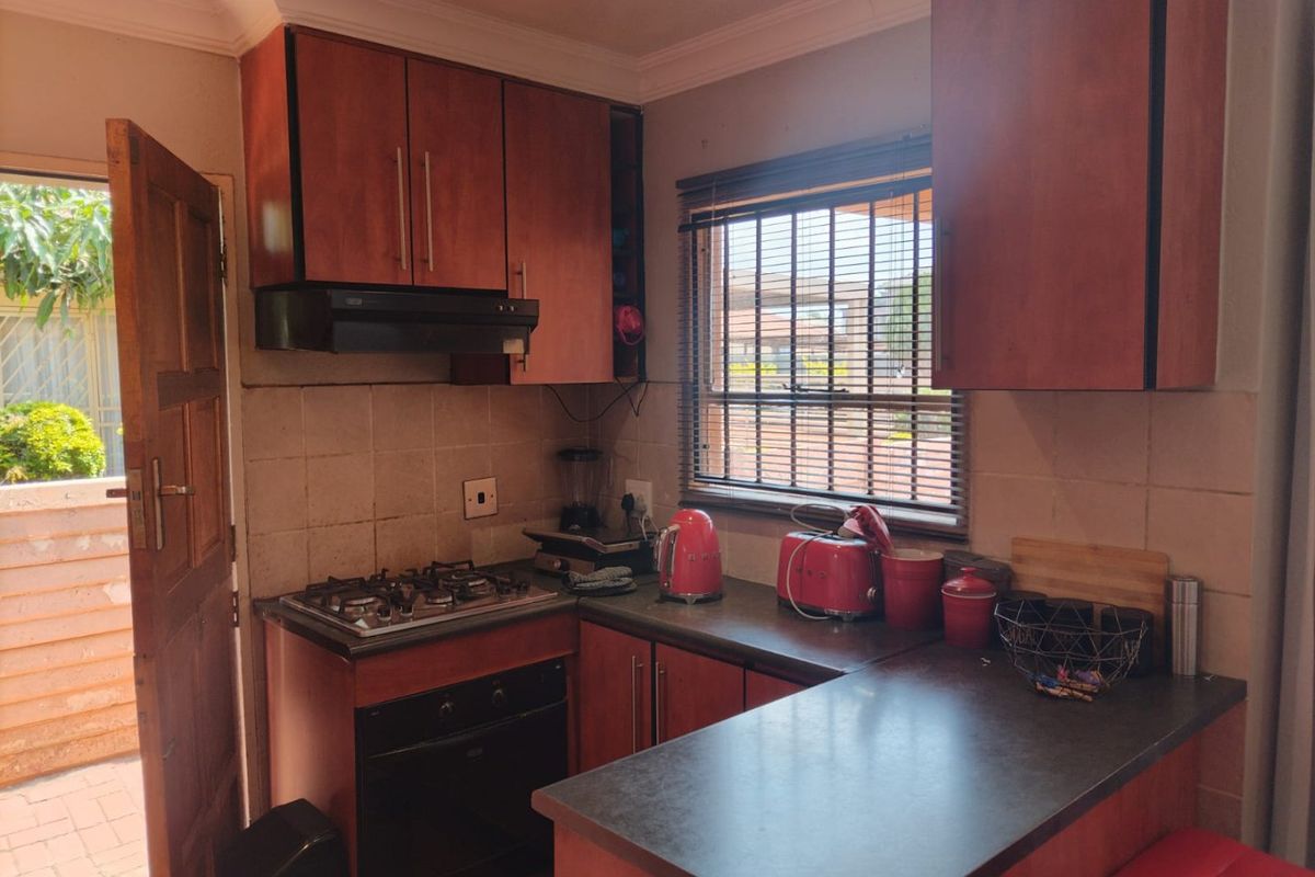 A functional kitchen featuring wooden cabinetry, a gas hob, built-in oven, and a tiled backsplash with direct access to the exterior.