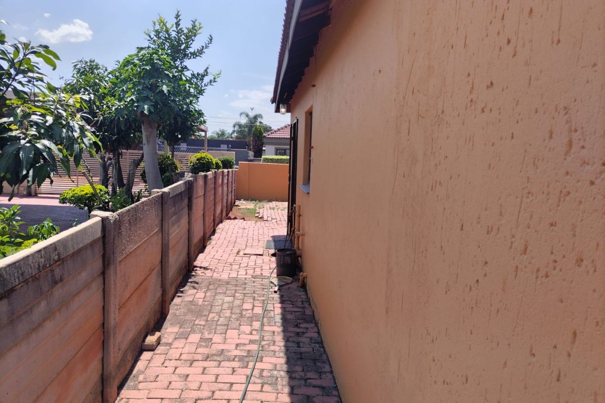 A side exterior walkway featuring paved flooring and a precast concrete boundary wall, showing signs of weathering on the exterior wall surface.