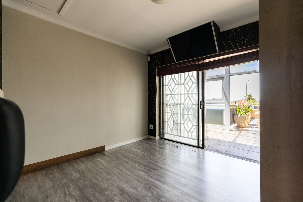An empty living room featuring laminate flooring and a sliding glass door that opens onto an outdoor patio area.