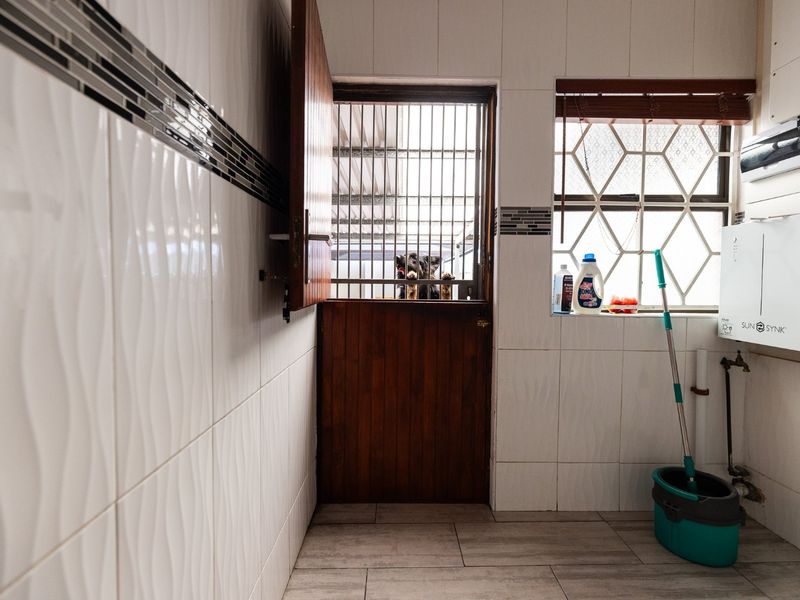 A functional laundry area featuring tiled walls and flooring, a secure dutch door, and an integrated inverter system.