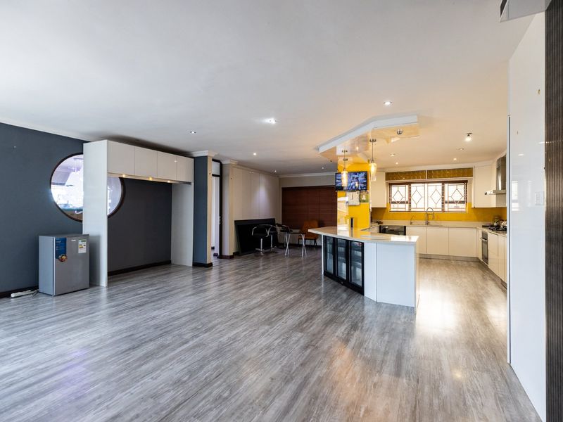 Spacious open-plan kitchen and living area featuring modern cabinetry, a central island with integrated appliances, and durable laminate flooring throughout.