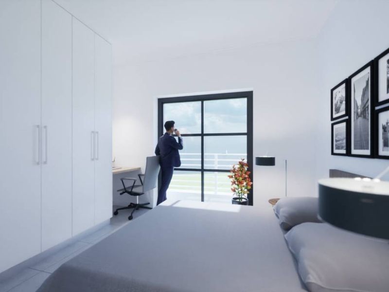 Modern bedroom featuring built-in wardrobes, a dedicated workspace, and a large window with access to a balcony.