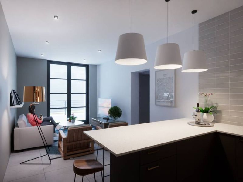 Modern open-plan living area featuring a sleek kitchen island with stone countertops, contemporary pendant lighting, and large windows providing ample natural light.