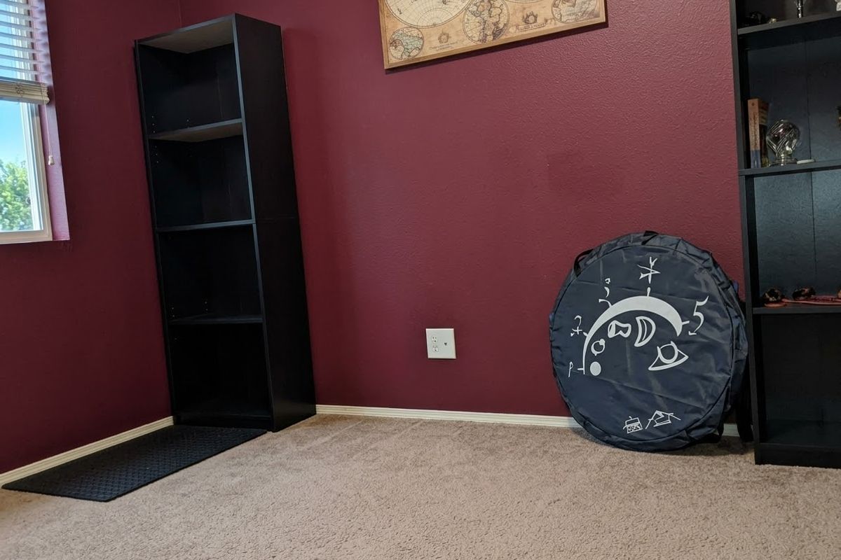 A bedroom featuring carpeted flooring, a window with blinds, and deep red painted walls.