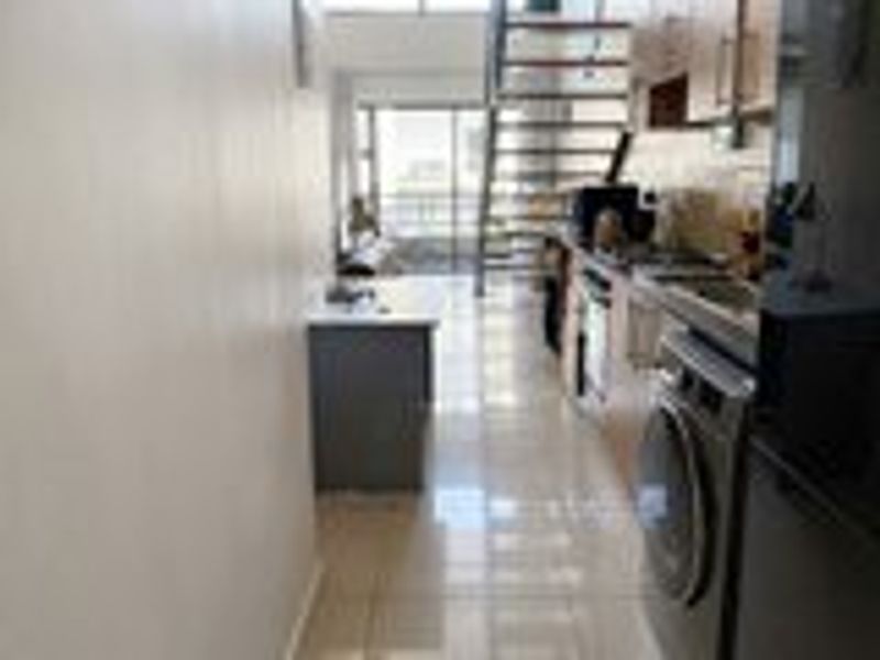 Open plan kitchen and living area featuring tiled floors, built-in cabinetry, and a staircase leading to an upper level.