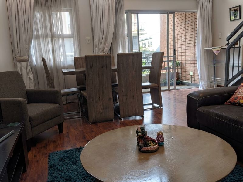 Open plan living and dining area featuring laminate flooring and direct access to a private balcony through sliding glass doors.