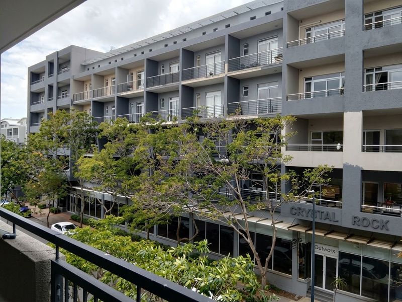 A view of the Crystal Rock apartment building facade, featuring multiple levels of balconies with metal railings and large windows.
