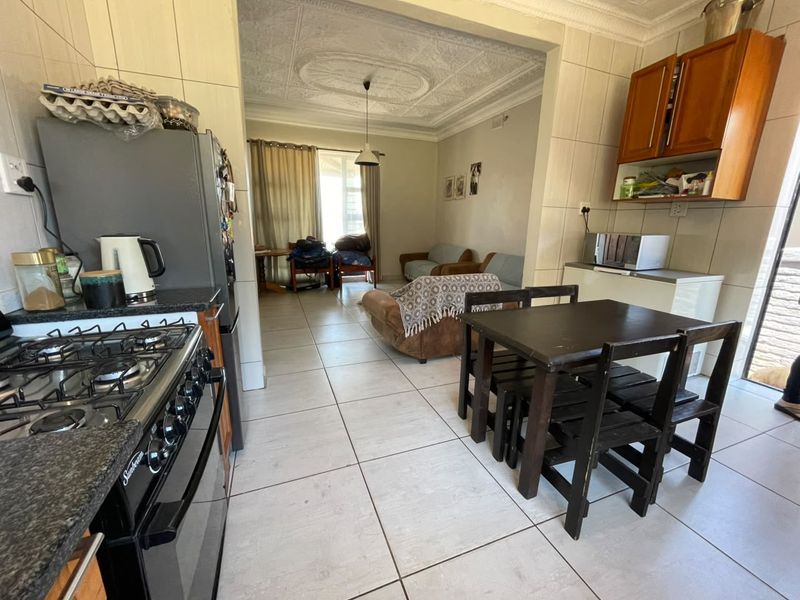 Open-plan kitchen and living area featuring tiled flooring, ornate ceiling detailing, and built-in cabinetry with a gas stove.