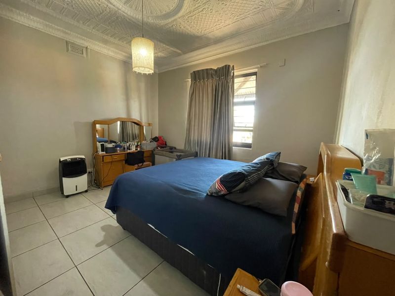 A bedroom featuring a distinctive ornate pressed metal ceiling, tiled flooring, and a window, offering a classic architectural foundation for potential updates.