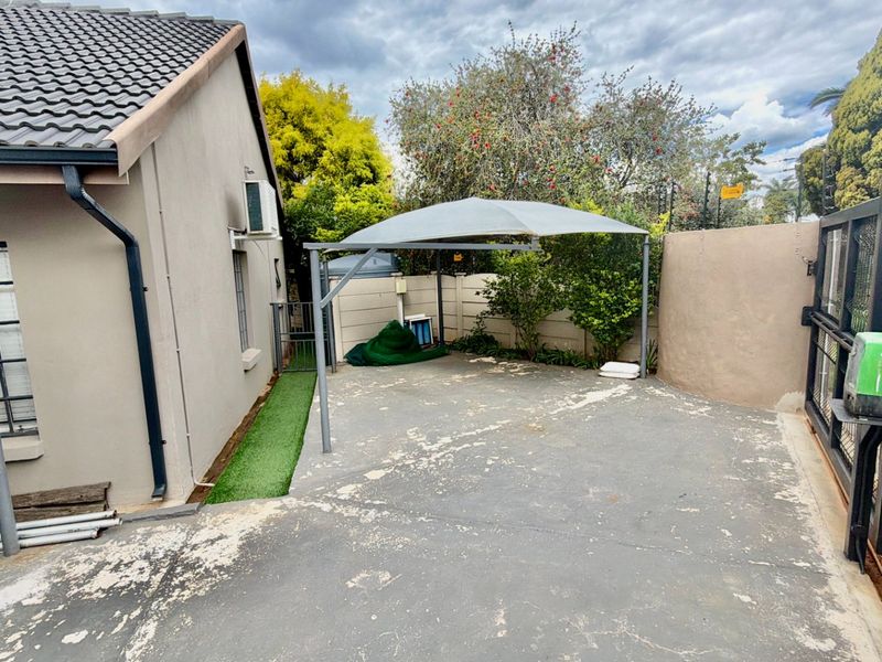 Rear courtyard area featuring a shade sail, concrete paving, and boundary walling, providing a functional outdoor space with potential for landscaping improvements.