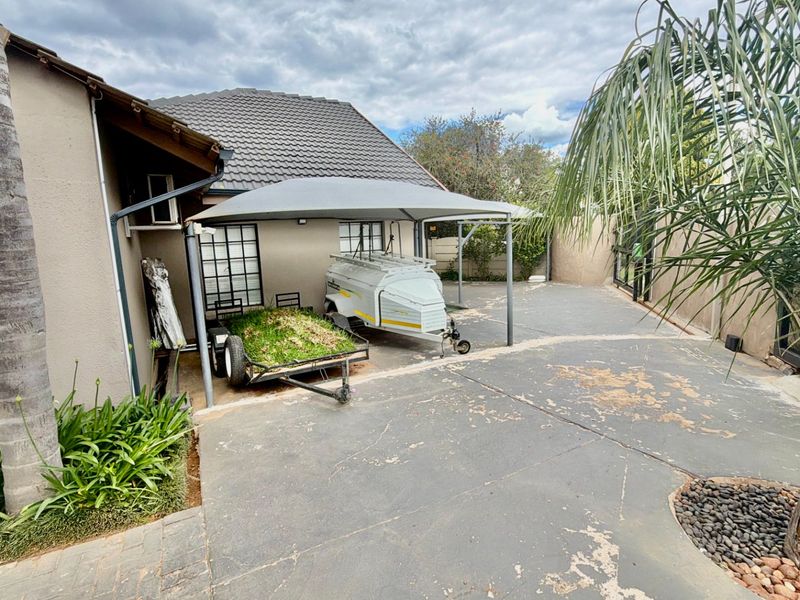 Rear exterior area featuring a concrete driveway, shade sail structure, and perimeter boundary walling.