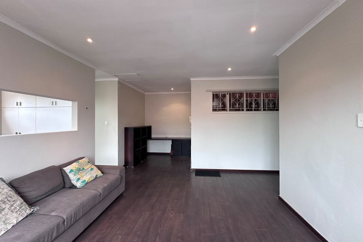 Spacious living area featuring dark laminate flooring, recessed downlighting, and a built-in desk nook, offering a versatile layout for relaxation or home office use.