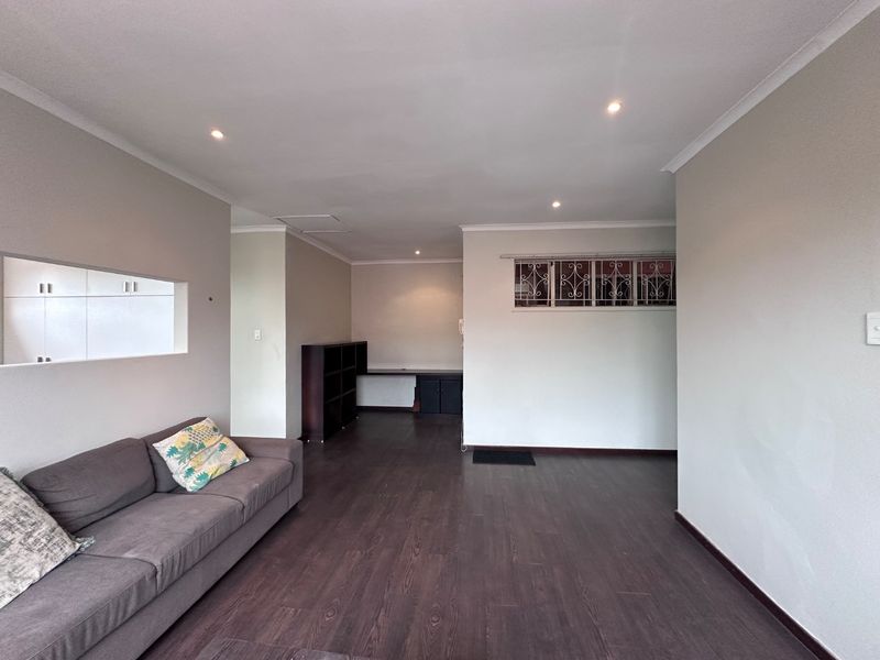 Spacious living area featuring dark laminate flooring, recessed downlighting, and a built-in desk nook, offering a versatile layout for relaxation or home office use.