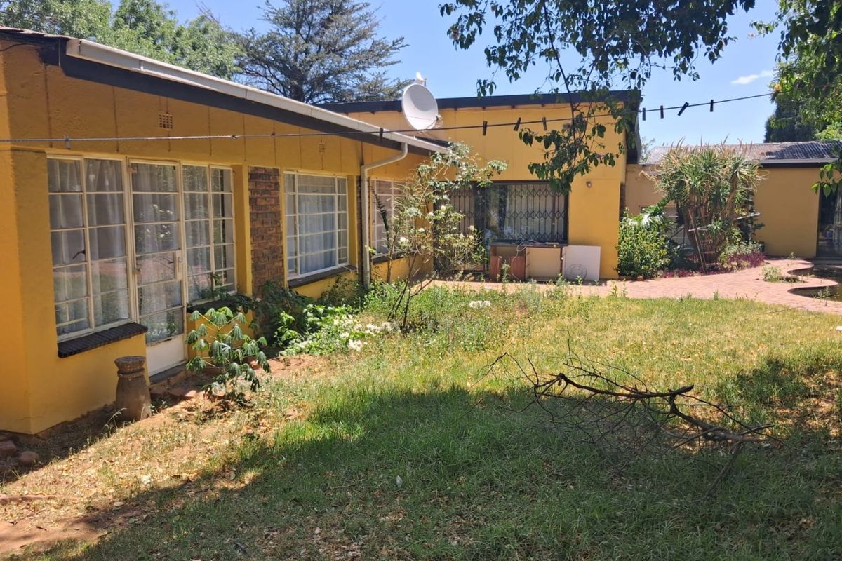 Rear view of the property featuring a paved patio area and garden space, showing potential for landscaping and exterior maintenance.